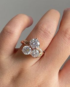 a woman's hand with a gold ring and two diamonds on top of it