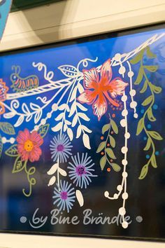 a close up of a window with flowers painted on the glass and words by blue brande