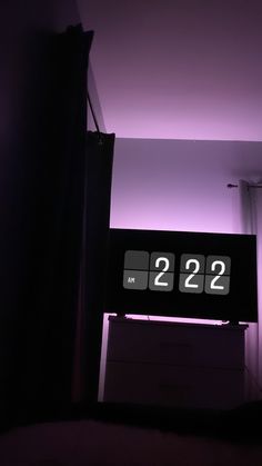 an alarm clock is lit up in the dark with purple lighting above it and below that reads 2 22