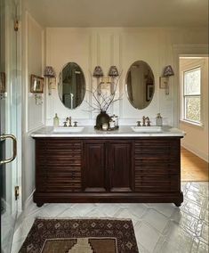 a large bathroom with double sinks and mirrors on the wall next to a rug in front of it