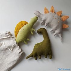 three stuffed dinosaurs sitting next to each other