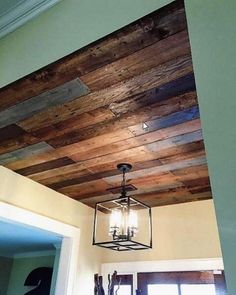 a light fixture hanging from the ceiling in a room with wood planks on it