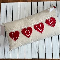 a red and white pillow sitting on top of a wooden floor next to a pair of scissors