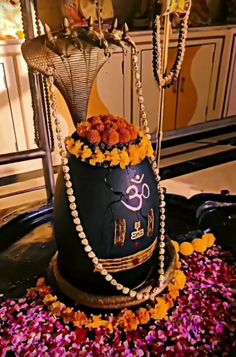 a decorated vase sitting on top of a metal bowl filled with flowers and chains hanging from it's sides