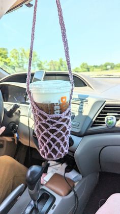 a coffee cup hanging from the handle of a car's steering wheel basket in a vehicle