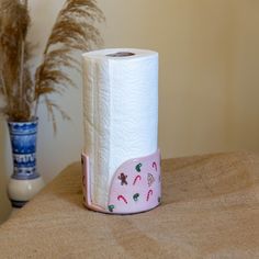 a roll of toilet paper sitting on top of a wooden table next to a potted plant