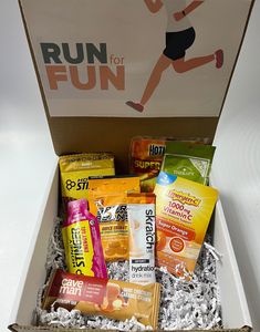 a box filled with snacks and drinks on top of a white countertop next to a sign that reads run for fun