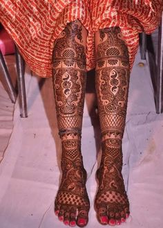 the legs and feet of a woman with henna tattoos on her body, sitting in a chair