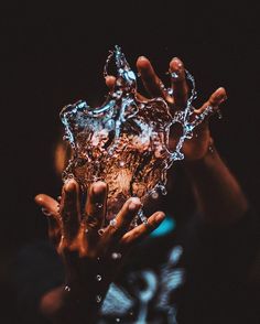 someone holding their hand up to the camera with water splashing on it's face