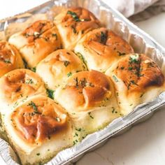 a pan filled with rolls covered in cheese and herbs