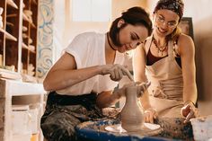 two women are making pottery on a potter's wheel