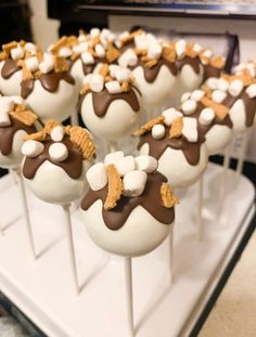 chocolate covered marshmallows with white and brown toppings on a stick in front of a microwave