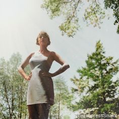 a woman standing in the grass with her hands on her hips