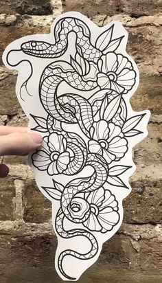 a hand holding up a sticker with a snake and flower design on the side