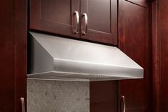 a stainless steel range hood in a kitchen with dark wood cabinets and marble countertops