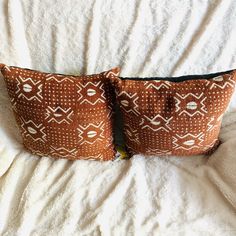 two brown and white pillows sitting on top of a bed next to eachother