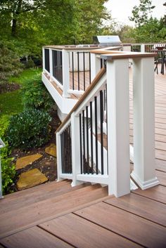 a wooden deck with white railings and wood steps leading up to a laptop computer on top of it