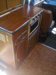 an oven and microwave in the back of a vehicle with wood paneling on the floor