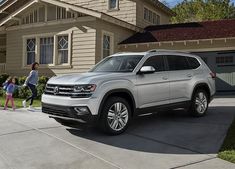 the new volkswagen atlastro is parked in front of a house with two children walking by