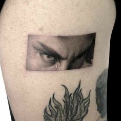 a man's upper arm with an eye and flames on it