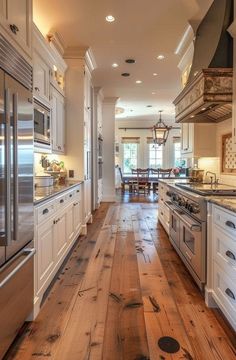 a large kitchen with white cabinets and wood flooring, along with stainless steel appliances