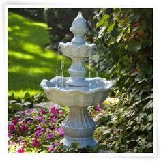 a water fountain surrounded by flowers and greenery