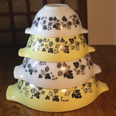 a stack of three yellow and white dishes sitting on top of a wooden table next to a wall