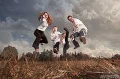 three people are jumping in the air with their hands up and one person is wearing white