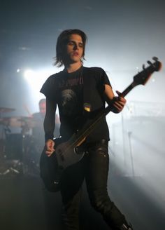 a man holding a guitar while standing on stage