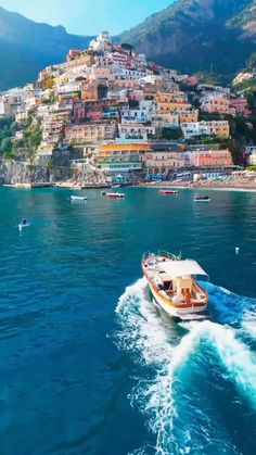 a boat is traveling through the water in front of a city on top of a hill