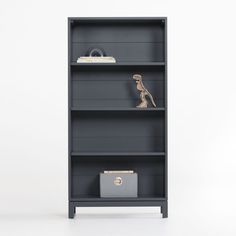 a grey bookcase with three shelves on each side and a small drawer in the middle