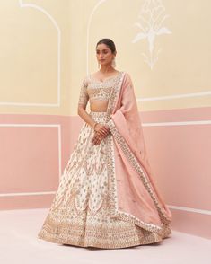 a woman in a white and pink lehenga