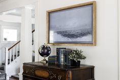 a painting hangs on the wall above a dresser