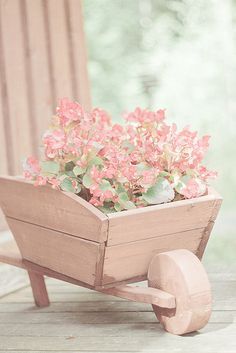 a wooden wheelbarrow with pink flowers in it