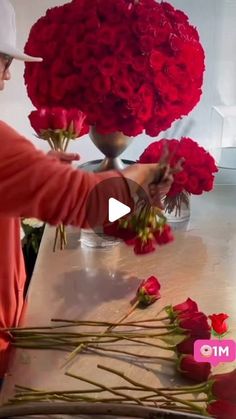 a woman arranging red roses on a table