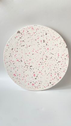 a white plate with pink and grey splatkles on the rim, against a white background