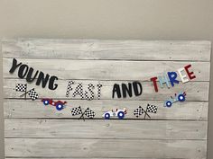 a wooden sign that says young, fast and three with race cars hanging from it