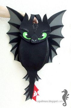 a black bat hanging on the wall with green eyes