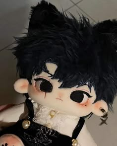 a doll with black hair and piercings on it's head sitting on a tile floor