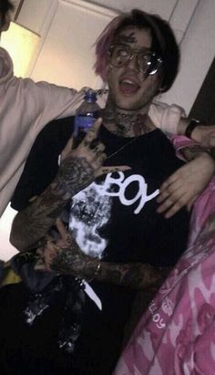 a man with pink hair and tattoos holding a bottle