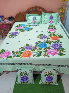 a bed with flowers on it in a room next to a green rug and wooden headboard