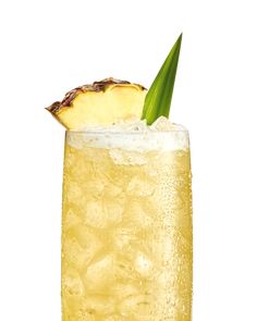 a tall glass filled with ice and a slice of pineapple on the rim, sitting on a white surface