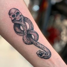 a skull and snake tattoo on the arm