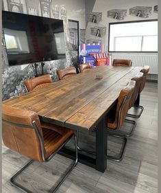 a large wooden table surrounded by brown leather chairs in front of a flat screen tv