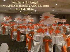 the tables are decorated with orange and white feathers for an elegant wedding or special event