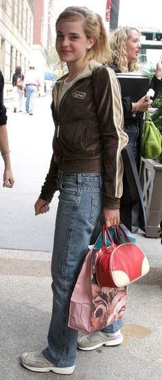 a woman is standing on the sidewalk with her handbag