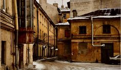 an alley way with snow on the ground and buildings in the backgrouds