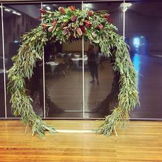 a wreath made out of branches and flowers sitting on top of a hard wood floor