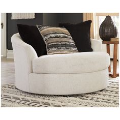 a white chair with black and brown pillows on it's back in a living room