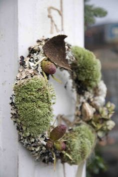 a wreath is hanging on the side of a white building with moss growing out of it